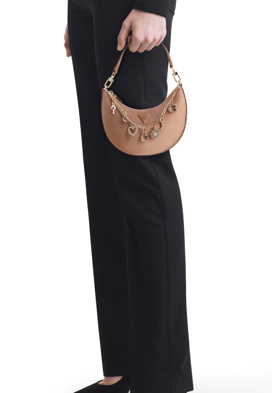 Beige schoudertas van Guess met goudkleurige ketting en glimmende bedeltjes, vastgehouden aan het handvat.