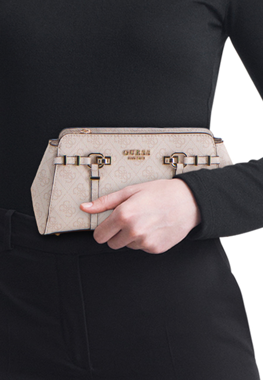 Beige schoudertas van Guess® met allover monogram G-patroon, goudkleurige gespdetails en ritssluiting, vastgehouden voor een zwarte outfit.