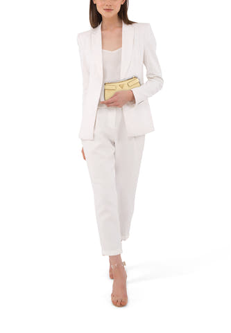 Gele schoudertas van Guess, gedragen met een witte damesbroek en blazer, en doorschijnende hakken.
