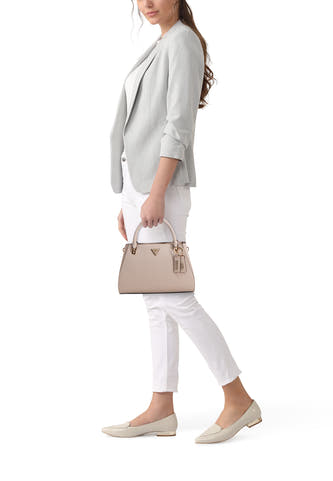 Sac à main beige de Guess, porté avec un blazer gris, un pantalon blanc et des chaussures de couleur crème.