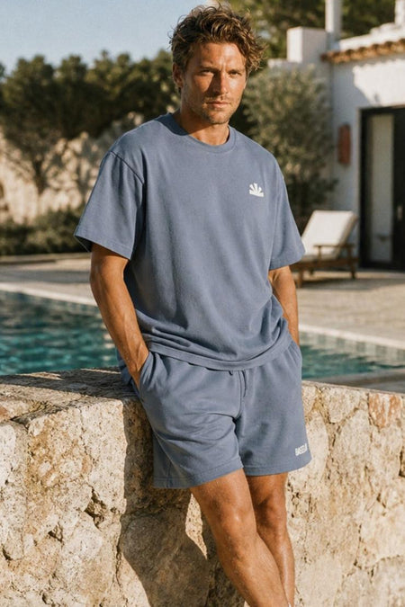 Blauwe korte mouwen t-shirt van BASELAB met klein wit logo, lifestyle shot bij zwembad, model in zijaanzicht