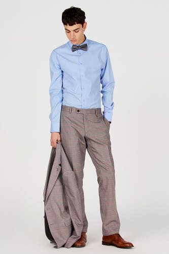 Chemise bleue à manches longues de Le Fabuleux Marcel de Bruxelles, portée avec un nœud papillon gris et un pantalon à carreaux.