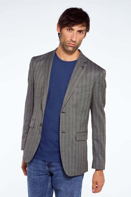 Blauwe blazer van Le Fabuleux Marcel de Bruxelles, met een subtiel visgraatpatroon, gecombineerd met een blauw T-shirt en jeans.
