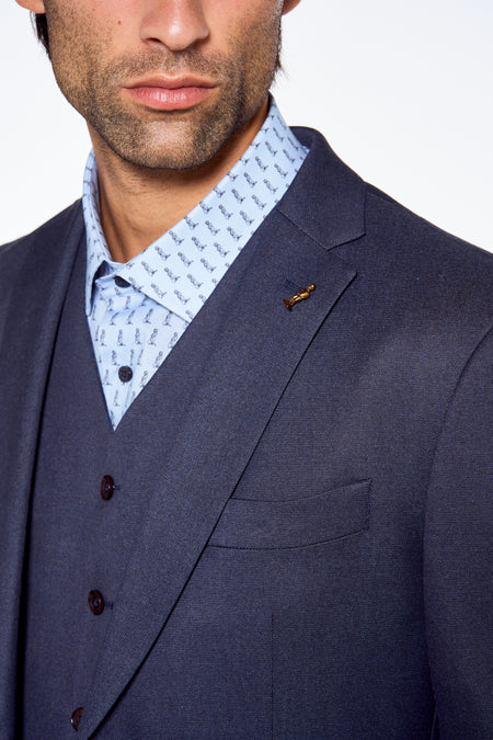 Donkerblauwe blazer van Le Fabuleux Marcel de Bruxelles, met gouden pin en gestreept overhemd, close-up voorzijde