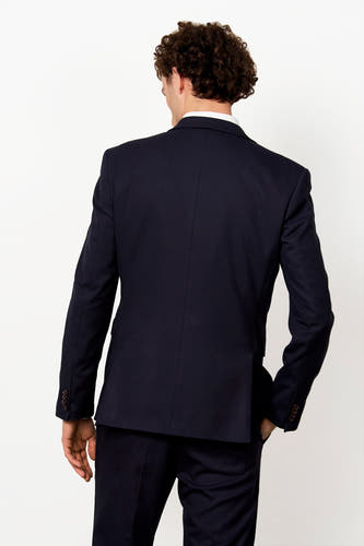 Donkerblauwe blazer van Le Fabuleux Marcel de Bruxelles, rugzicht, met lange mouwen, bruine knopen en een witte blouse.