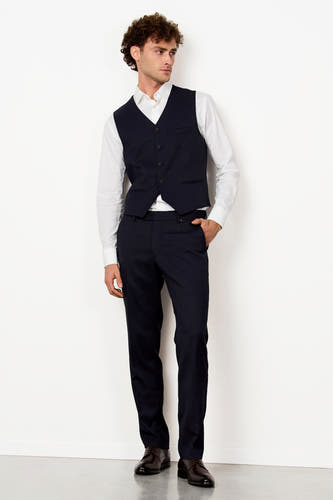 Gilet bleu de Le Fabuleux Marcel de Bruxelles, associé à une chemise blanche et un pantalon propre, sur un fond blanc.