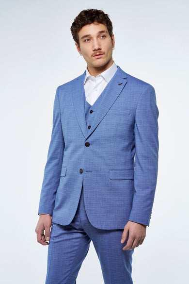 Blauwe blazer van Le Fabuleux Marcel de Bruxelles, met een subtiel ruitpatroon, gedragen met een vest en wit overhemd.