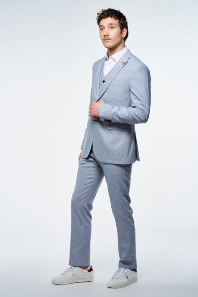Blauwe blazer van Le Fabuleux Marcel de Bruxelles, gedragen met wit overhemd, vest en witte sneakers.