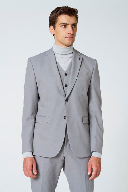Beige blazer van Le Fabuleux Marcel de Bruxelles, met een vest en rolkraagtrui eronder, effen en met knoopsluiting.
