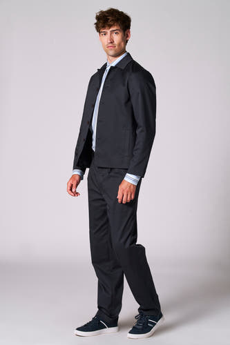 Blauwe blazer van Le Fabuleux Marcel de Bruxelles, gedragen over een gestreept overhemd en zwarte broek, met blauwe suède schoenen.
