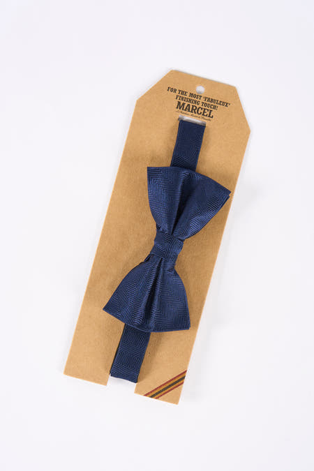 Ruban bleu de Le Fabuleux Marcel de Bruxelles, avec un motif de poissons subtil, présenté sur une étiquette en carton.