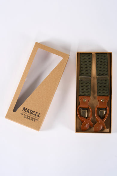 Ceinture verte de Le Fabuleux Marcel de Bruxelles, dans une boîte en carton avec une ouverture triangulaire transparente.
