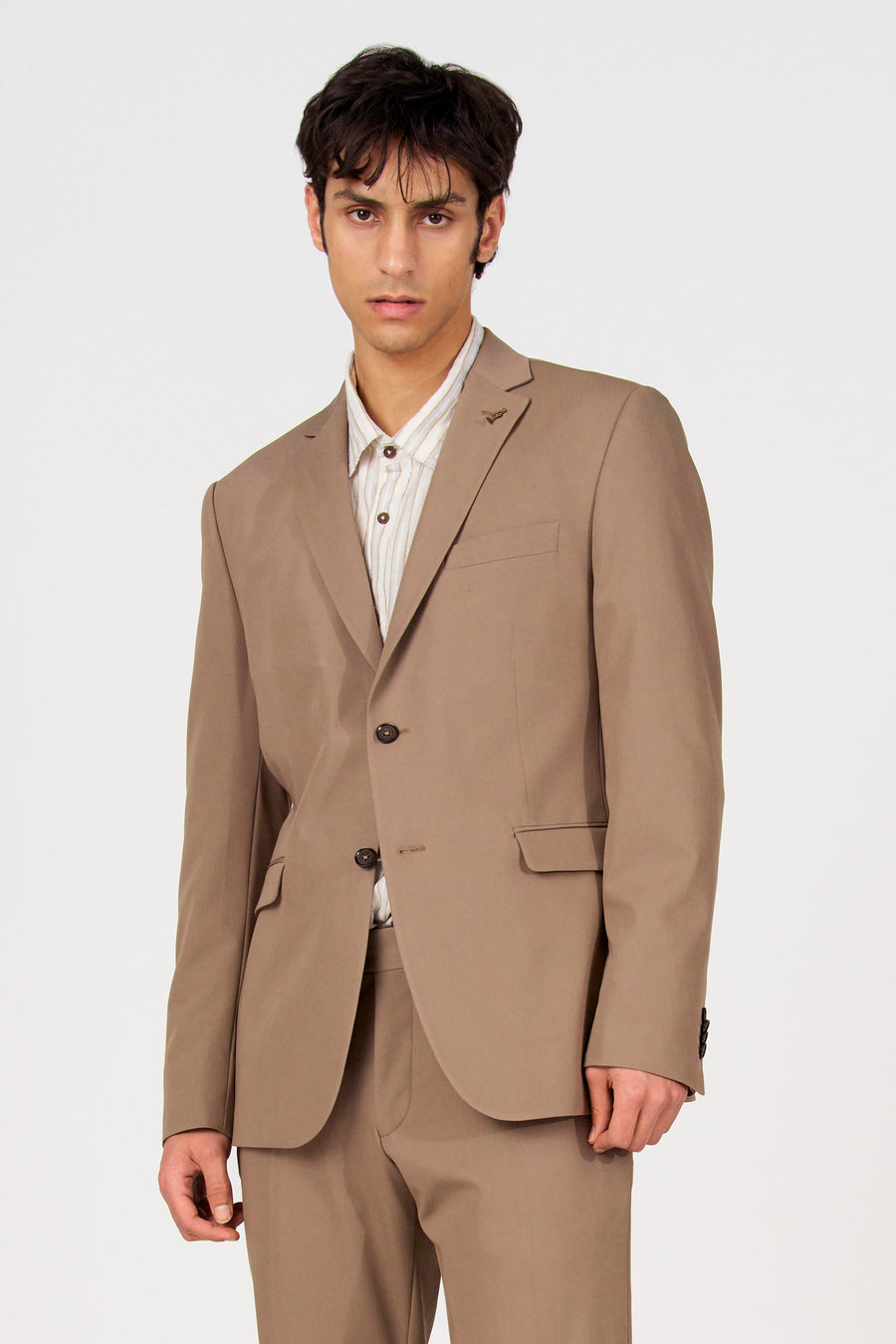 Bruine blazer van Le Fabuleux Marcel de Bruxelles, met knoopsluiting en opgestikte zakken, gedragen over een gestreept overhemd.