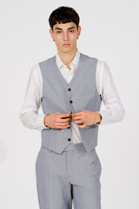 Blauw gilet van Le Fabuleux Marcel de Bruxelles, gedragen over een wit overhemd met lange mouwen en een bijpassende broek.