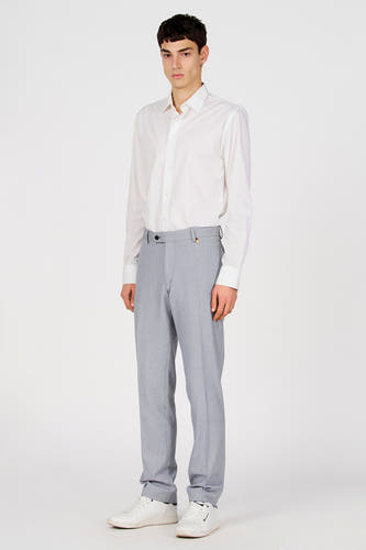 Pantalon de costume bleu de Le Fabuleux Marcel de Bruxelles, avec une texture subtile et une coupe classique, combiné avec une chemise blanche et des baskets blanches.