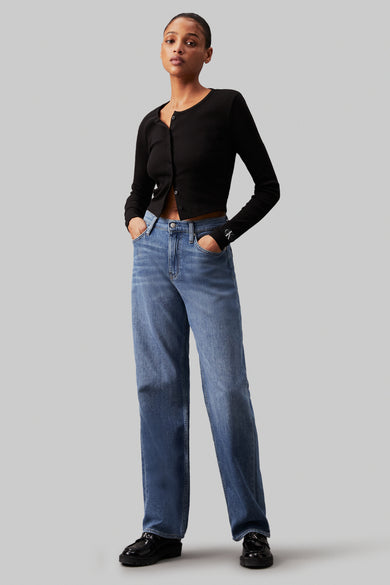 Jean bleu large de Calvin Klein, associé à une veste noire et des chaussures noires.