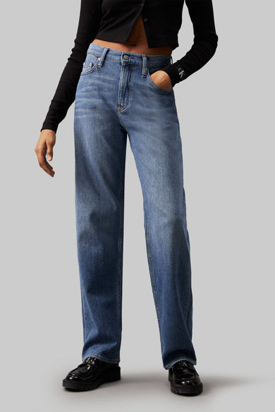 Jean décontracté de denim bleu Calvin Klein, avec un haut noir et des chaussures noires.
