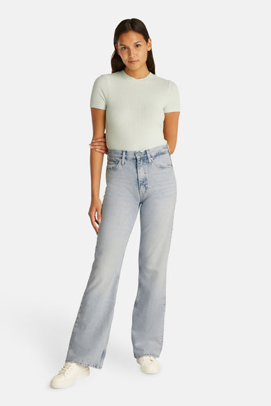 Jeans bootcut van lichtblauw denim van Calvin Klein, gedragen met een shirt met structuur en witte sneakers.
