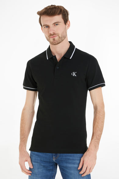 Polo noire Calvin Klein, à manches courtes et avec un passepoil blanc le long du col et des manches.