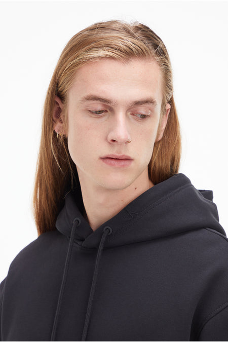 Zwarte hoodie van Calvin Klein met capuchon en trekkoord, close-up op de schouder en kraag.