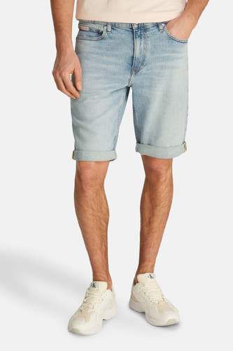 Jean court en denim bleu clair de Calvin Klein, avec des poches froncées et associé à un T-shirt.