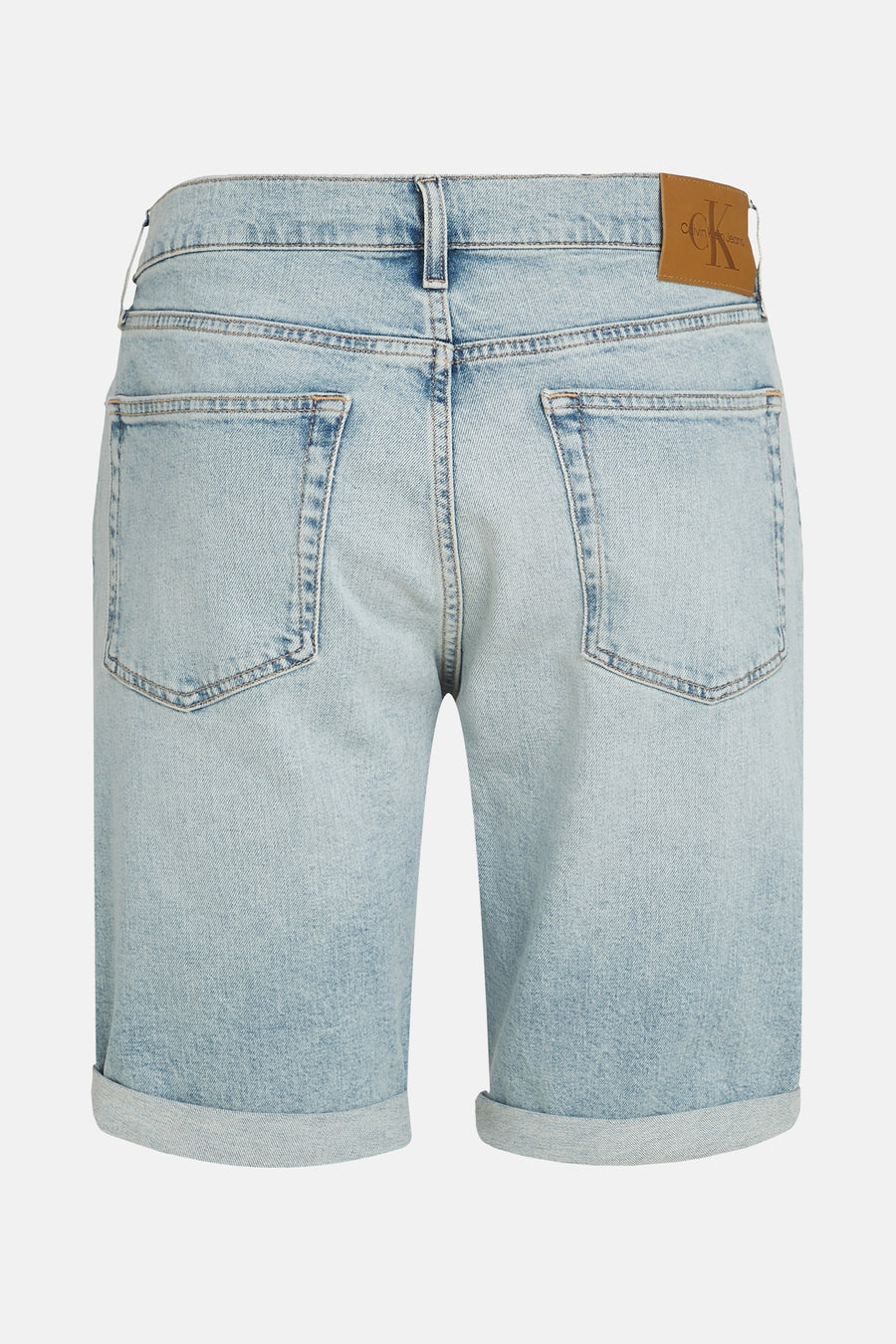 Jean court en denim bleu clair de Calvin Klein, avec des poches rabattues et une étiquette en cuir marron sur la ceinture.