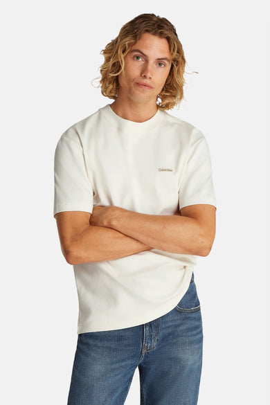 T-shirt écru à manches courtes de Calvin Klein, porté avec un jean bleu.