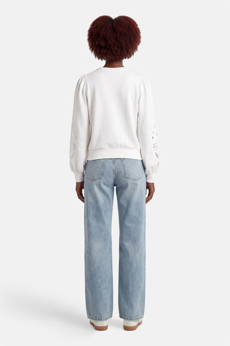 Witte sweater van HAILYS met lange mouwen met bloemmotief en lichtblauwe jeans.
