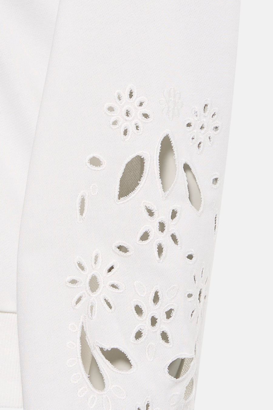 Pull blanc de HAILYS, avec motifs floraux décoratifs et perforations sur la manche.