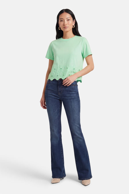 Groen T-shirt met korte mouwen van HAILYS, met bloemendetails aan de zoom en gedragen met donkere jeans en hakken.