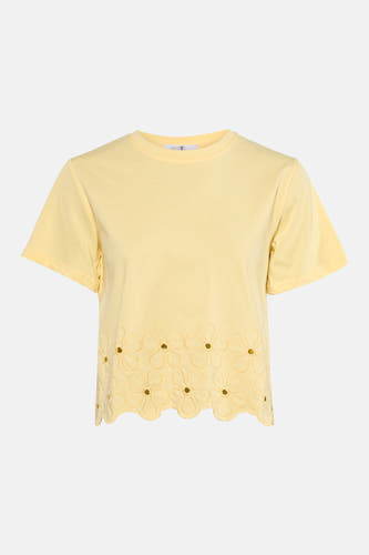 T-shirt jaune à manches courtes de HAILYS, fini avec broderie le long de l'ourlet, combiné avec un jean bleu foncé et des talons nude.