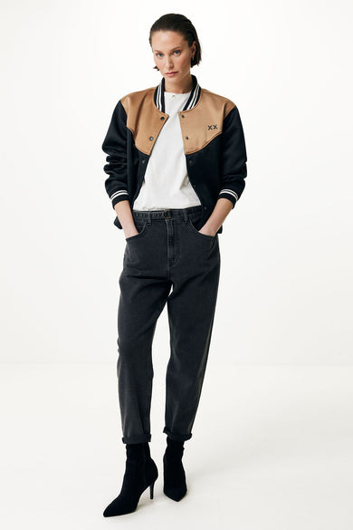 Zwarte korte jas van MEXX, met bruine schouders en gedragen met een wit T-shirt, jeans en zwarte laarsjes.
