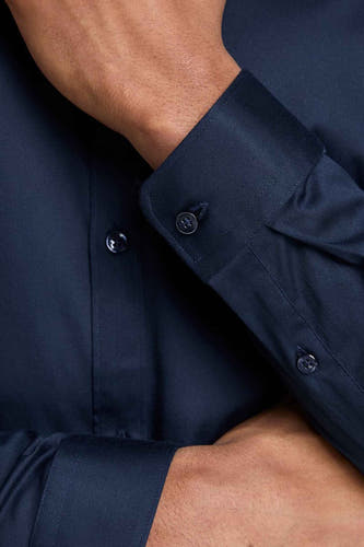 Blauw overhemd met lange mouwen van PREMIUM by JACK & JONES, close-up met knoopdetail en gekruiste armen.