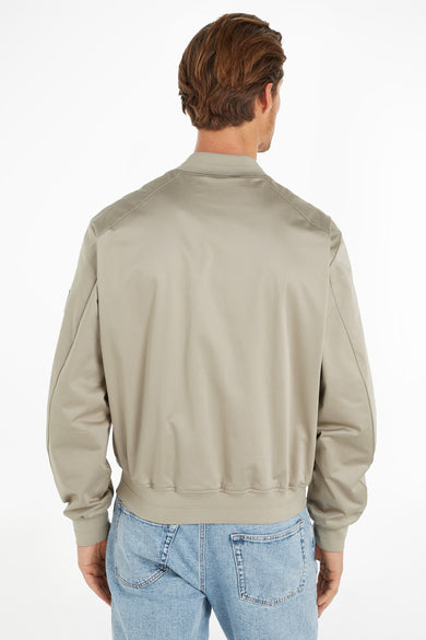 Ecru korte jas van Calvin Klein, gezien van de achterkant, met een geribbelde kraag, manchetten en zoom, gedragen met een lichte spijkerbroek.