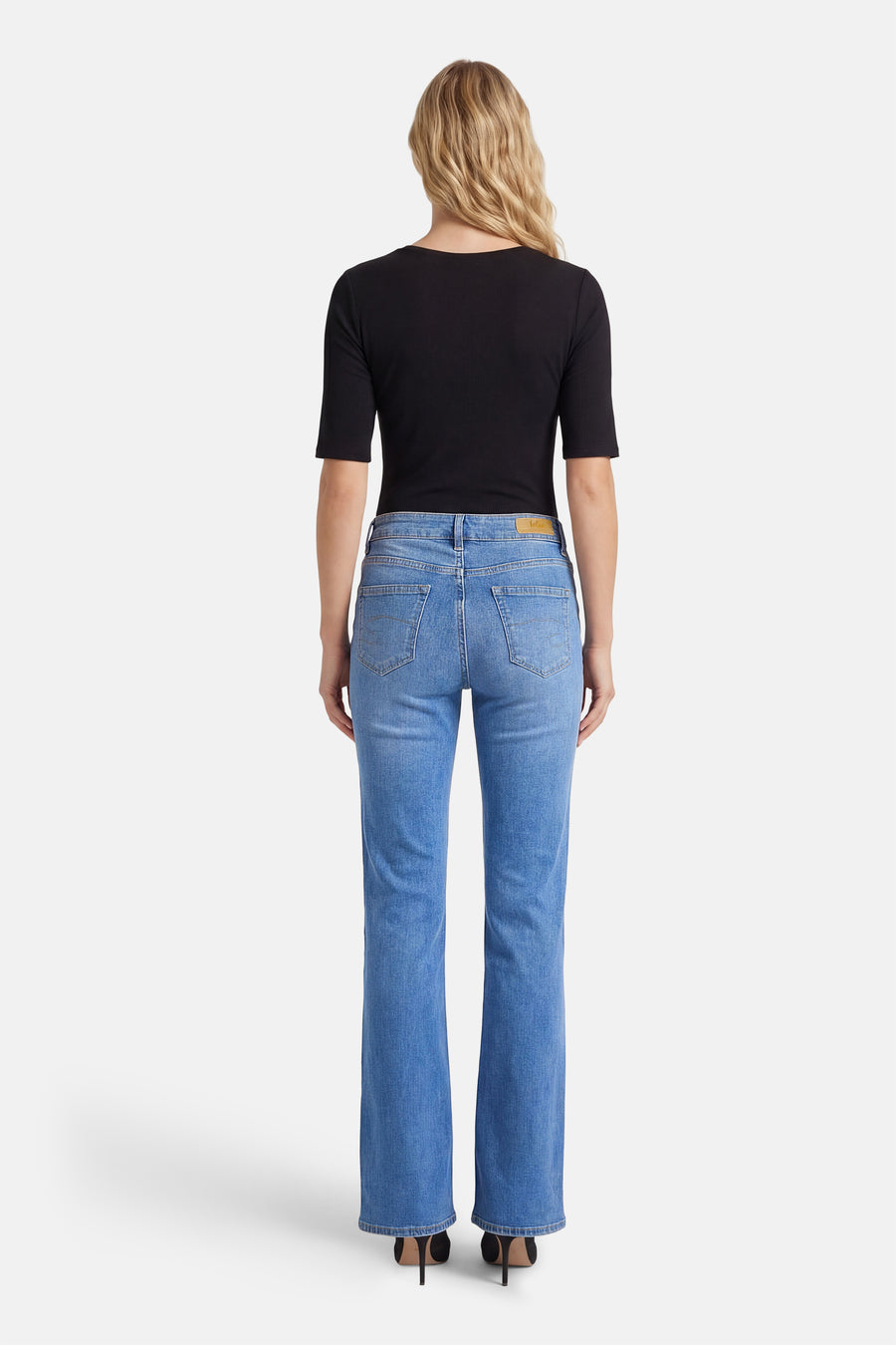 Jean évasé bleu clair de Lee Cooper, vu de dos, avec un haut noir et des talons.
