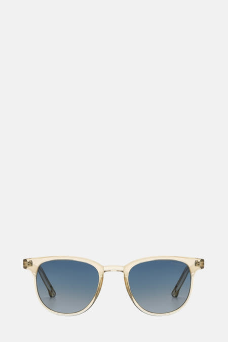 Lunettes de soleil bleues de KOMONO, portées par un modèle avec une chaîne couleur argent sur un fond blanc.