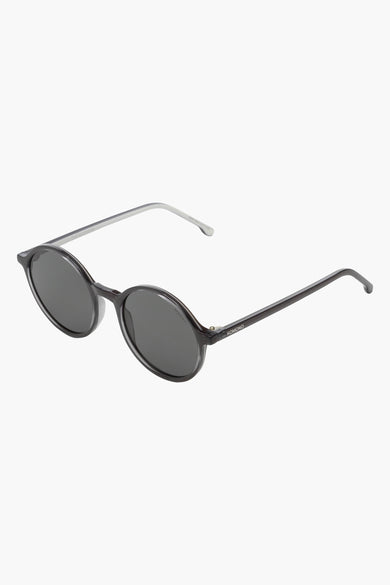 Lunettes de soleil grises de KOMONO, avec des verres ovales et des branches fines couleur argent.