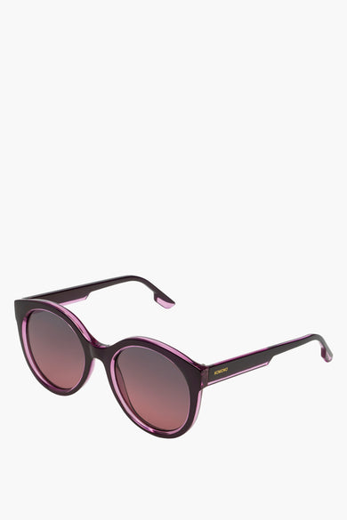 Lunettes vertes de KOMONO, avec monture violette et verres teintés foncés.