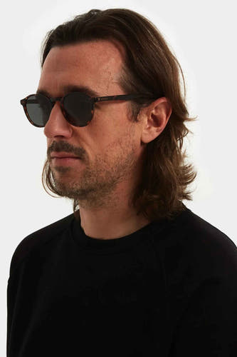 Bruine zonnebril van KOMONO, met een gevlekte print en gedragen door een man met een zwart shirt.
