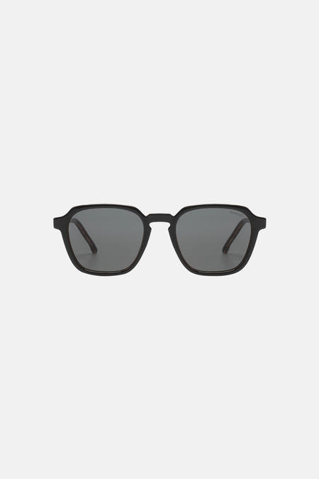 Lunettes de soleil noires de KOMONO, avec une monture minimaliste et des verres foncés.