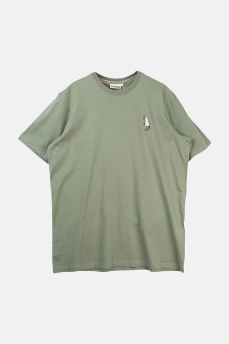 Groen T-shirt met korte mouwen van LAKOR, met een kleine pinguïn illustratie op de borst.
