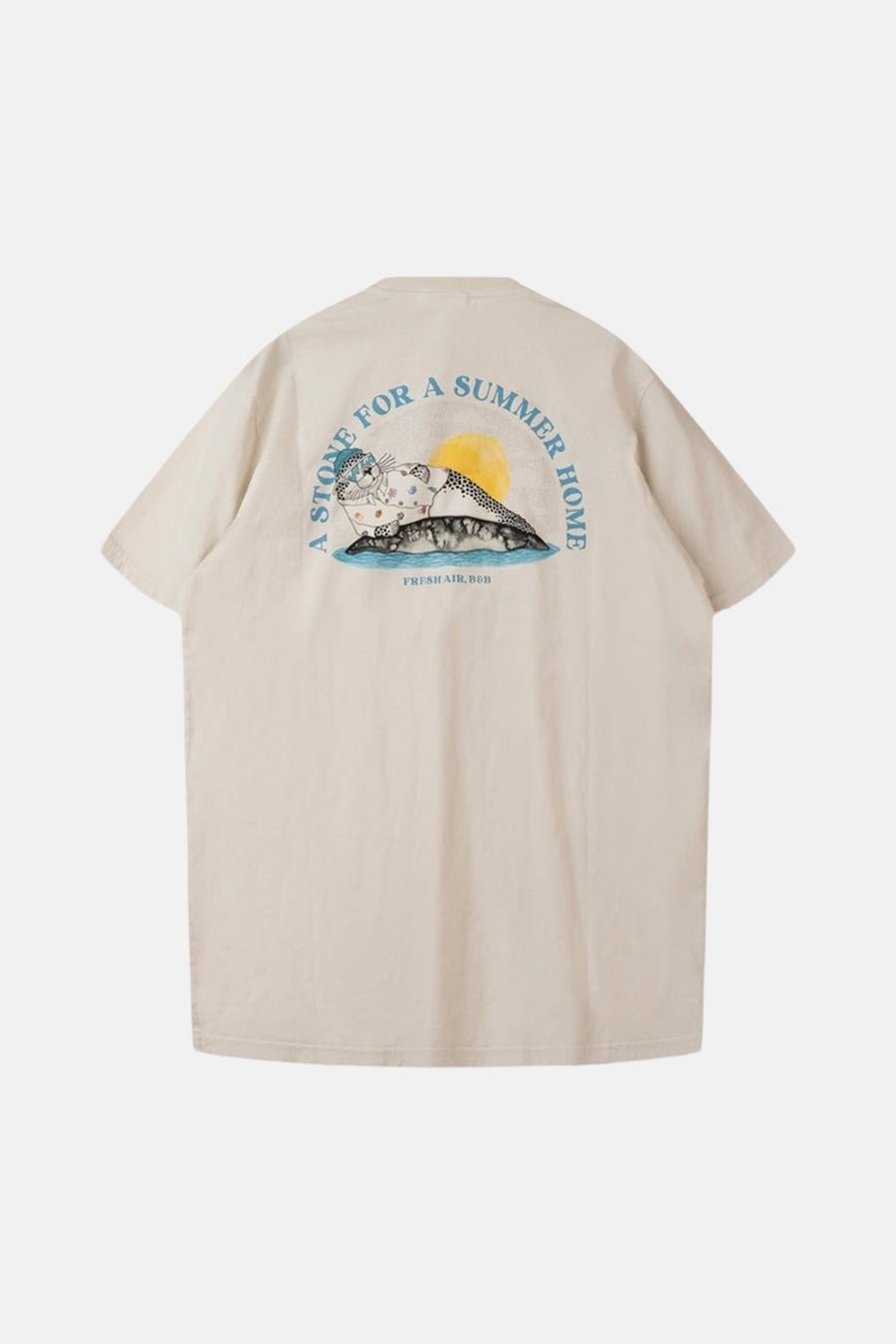 Ecru T-shirt van LAKOR, met een print van een zeehond en de tekst 'A stone for a summer home' op de achterkant.