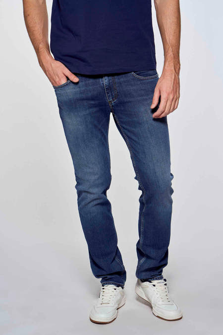 Slim jeans in mid blue denim van Lee Cooper®, met subtiele fijn gewassen textuur, strakke pasvorm en lichte verbleek effecten, gedragen met donkerblauw shirt en witte sneakers.