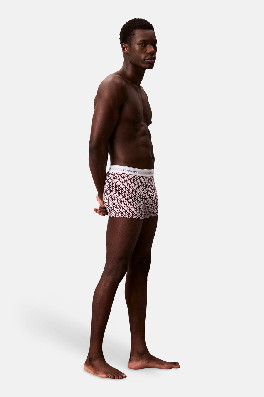 Boxer shorts met meerkleurige monogramprint van Calvin Klein, met witte tailleband, gedragen door een man in zijprofiel.