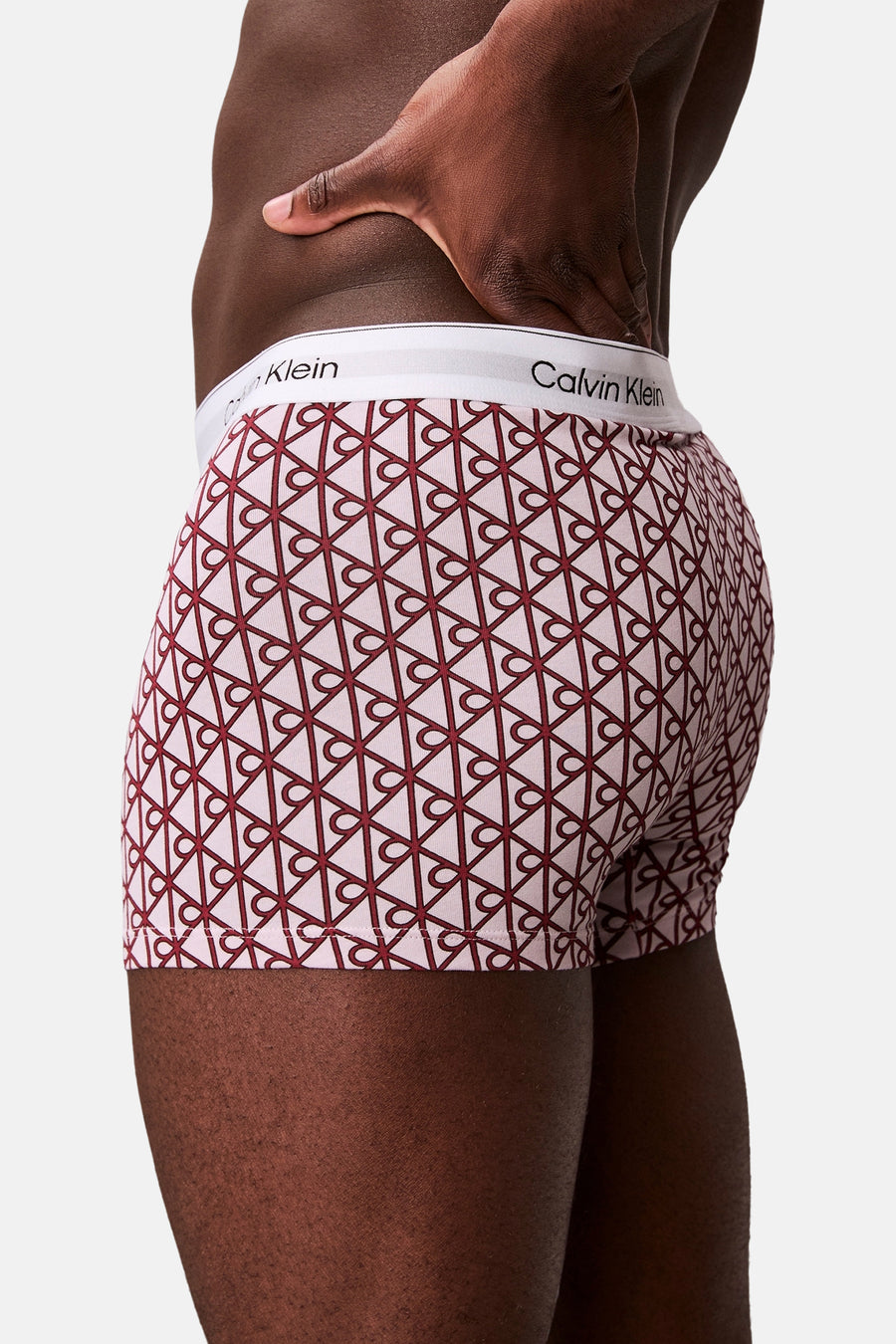 Lichtroze boxershort van Calvin Klein met donkerrood geometrisch patroon en witte tailleband, zij-achterzicht.