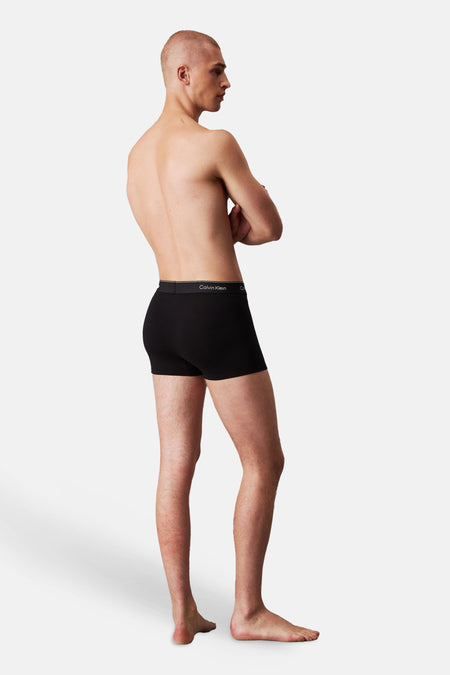Zwarte boxershort van Calvin Klein gedragen door een man, staand in zijprofiel met gekruiste armen, met zichtbare logoband.