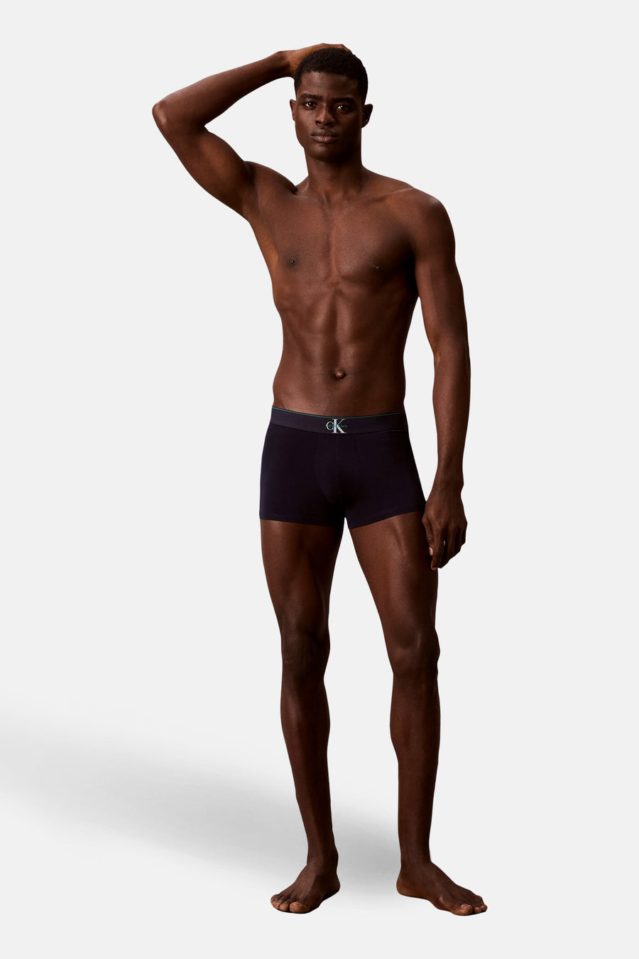 Zwarte boxershort van Calvin Klein, gedragen door een mannelijk model met een ontbloot bovenlichaam, staand tegen een witte achtergrond.