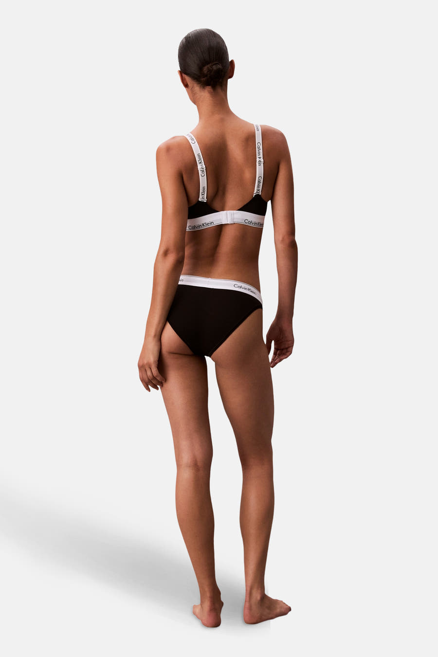 Zwarte beha van Calvin Klein, met witte banden met logo, gezien van achteren.
