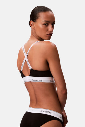 Zwarte beha van Calvin Klein met gekruiste bandjes en een witte elastische band met logo, gezien van achteren.
