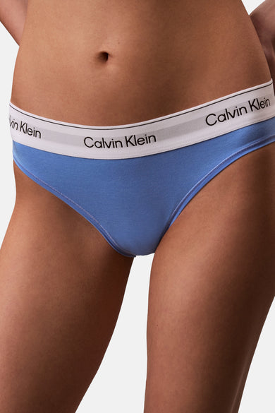 Culotte bleue Calvin Klein, avec bande blanche et logo, portée par un mannequin avec un soutien-gorge bleu assorti.